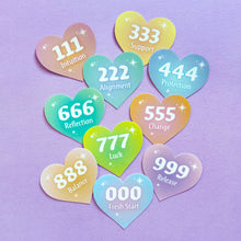 Load image into Gallery viewer, Overhead flat lay of a spread of colorful heart-shaped stickers with angel numbers and corresponding text, on top of a purple background.

